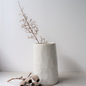 These sculptural vessels have been wheel thrown and then carved at different angles to capture the reflections of light on the glossy white surface.  They are striking yet unassuming, making them the perfect vessel to hold any bouquet or utensil.